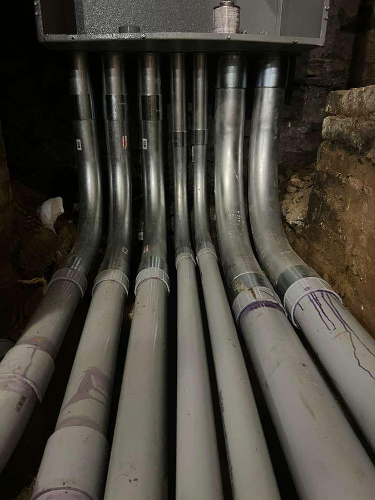 Bank of riser conduits transitioning from PVC to rigid metal into overhead equipment