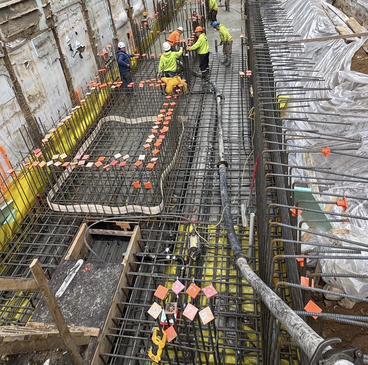 Overhead view of an AGC foundation excavation with a full rebar mat and crew preparing the slab