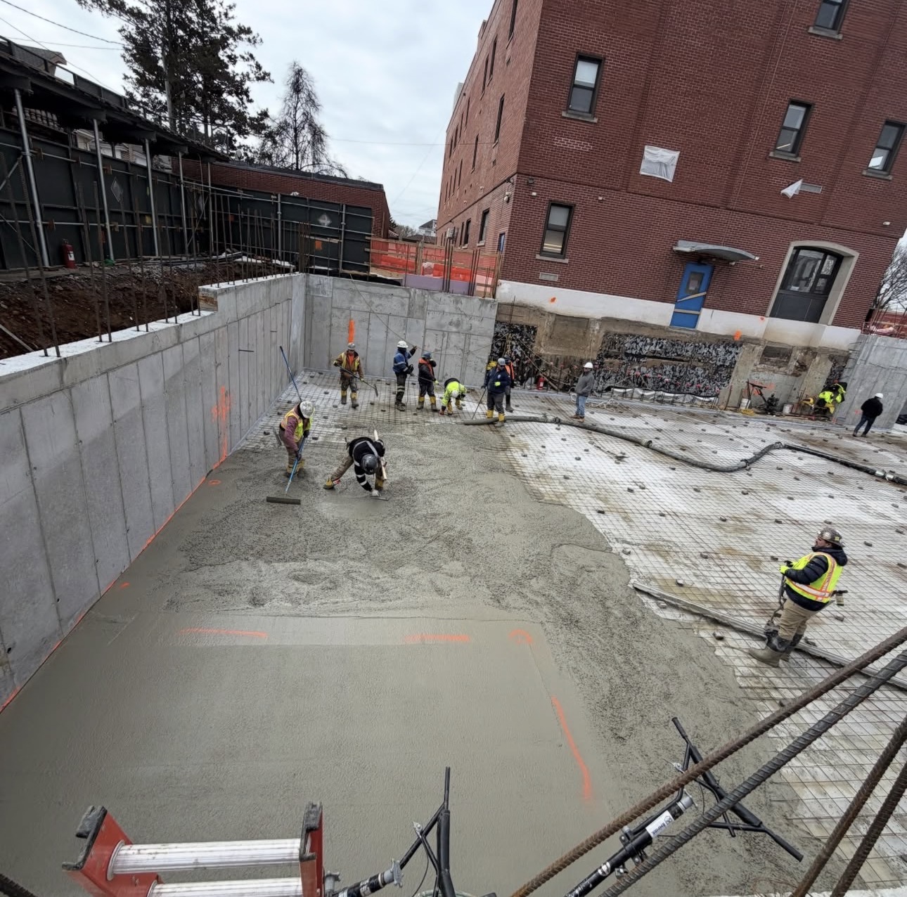 AGC crew placing and finishing a structural mat-slab concrete pour on a commercial construction site