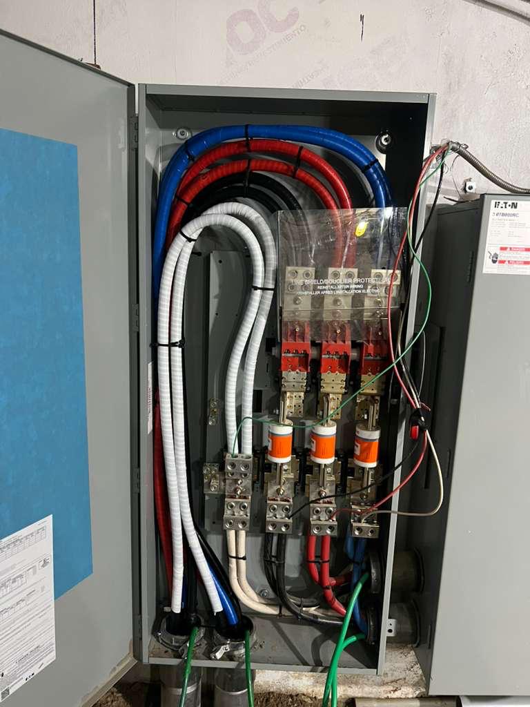 Open commercial disconnect enclosure with colour-coded feeder conductors terminated at the lugs