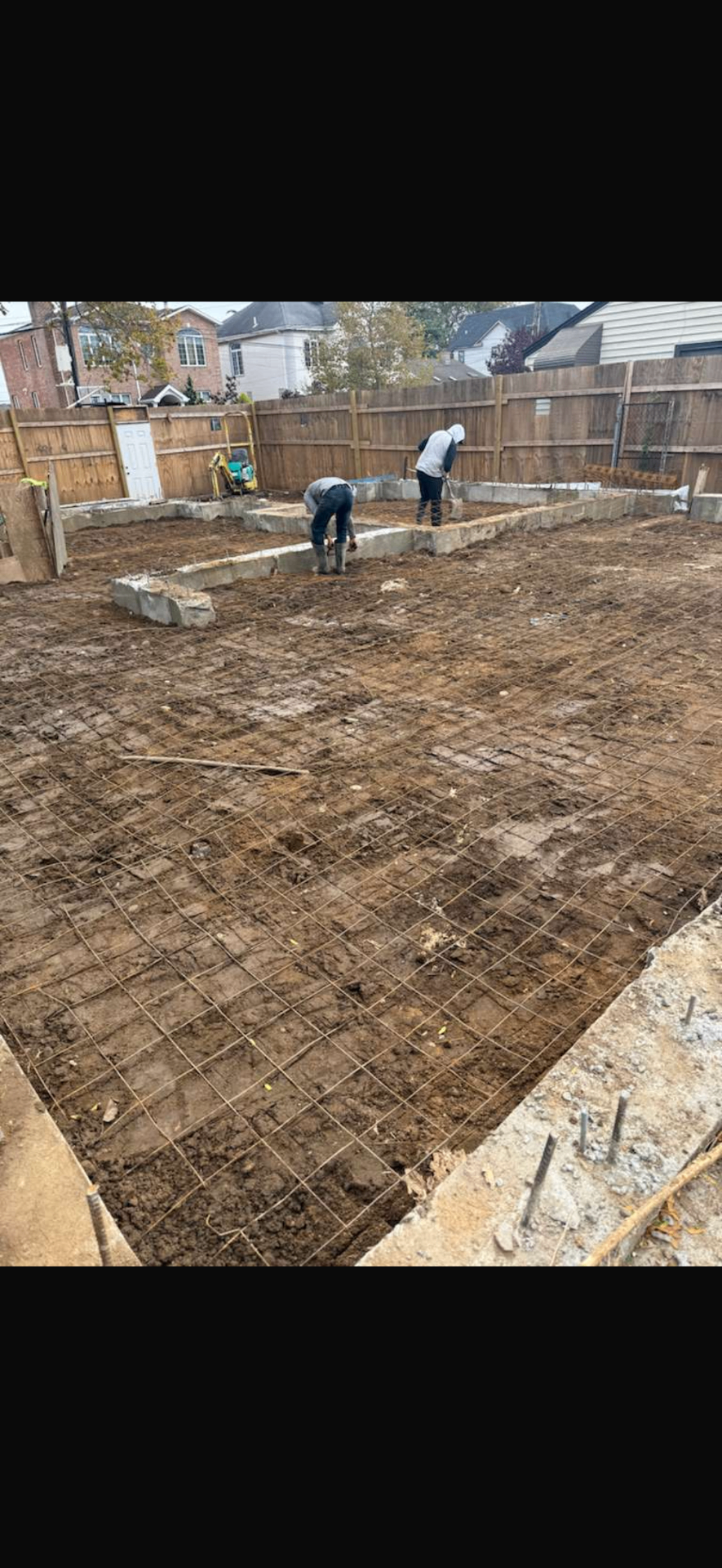 AGC crew setting welded wire mesh across a slab area between poured foundation walls
